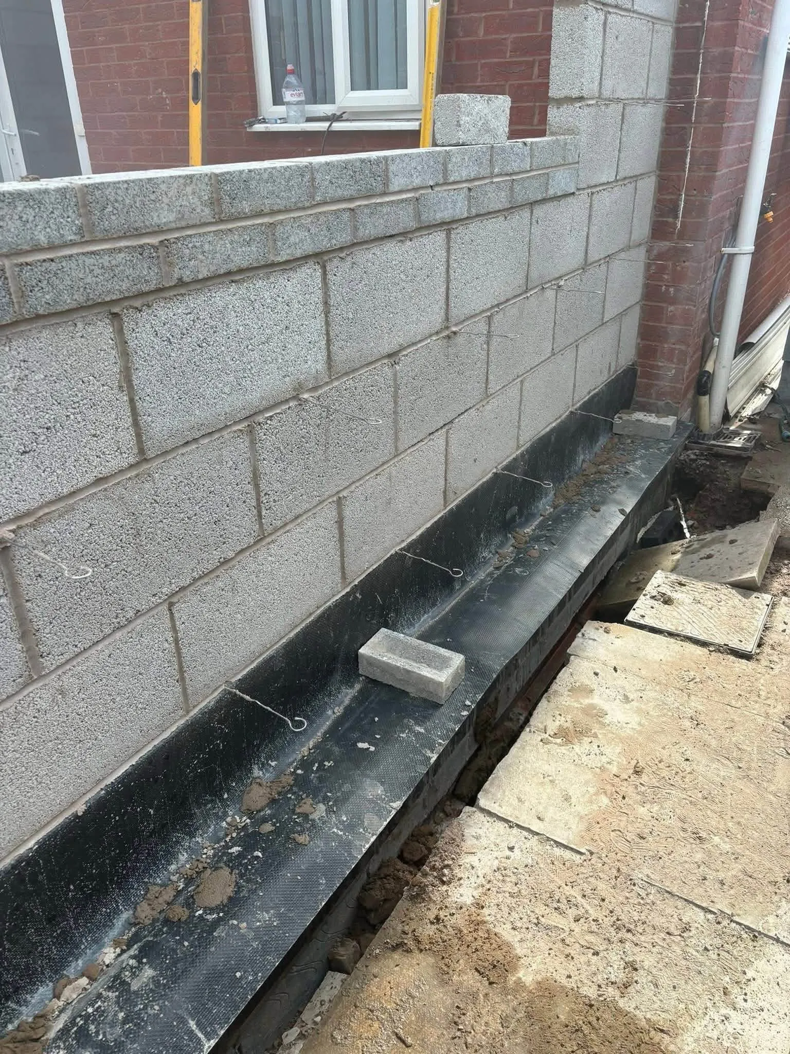 New blockwork wall with a black damp-proof layer along its base