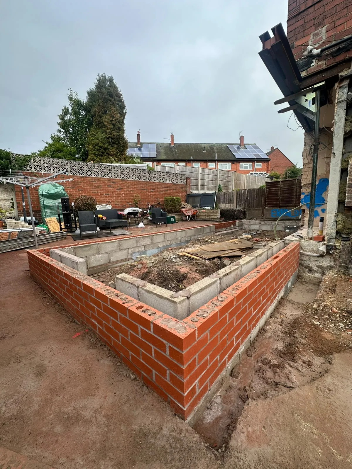 Neat red brick walls built up from new foundations in a back garden