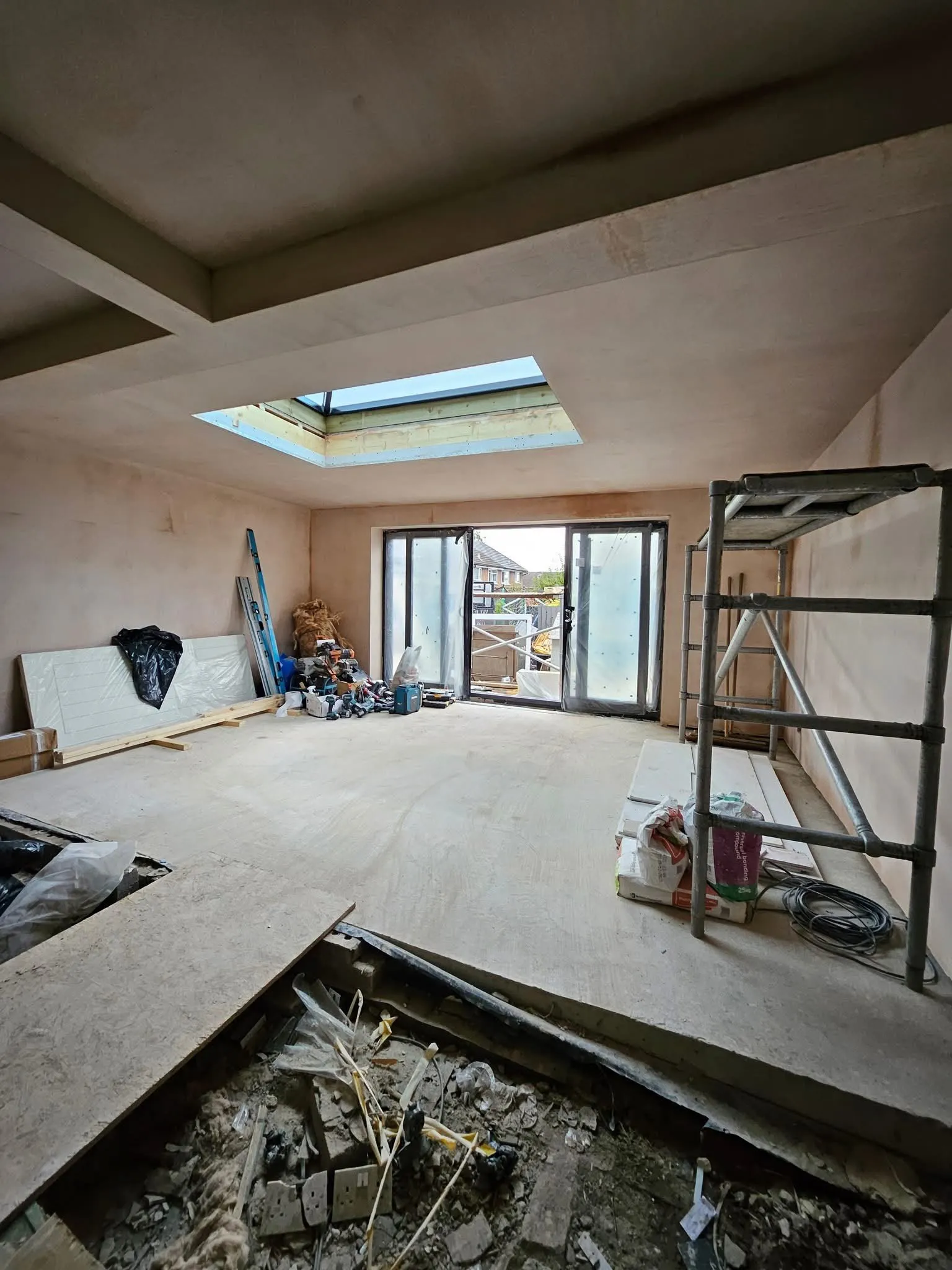 Inside a new extension with fresh plaster, a roof lantern and glass doors to the garden
