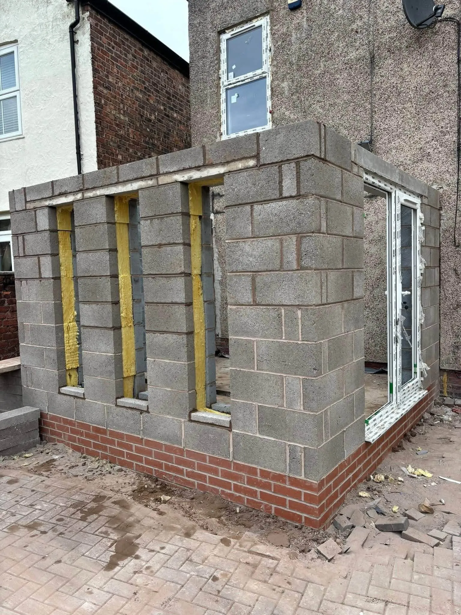 Single-storey extension in grey blocks on a red brick base