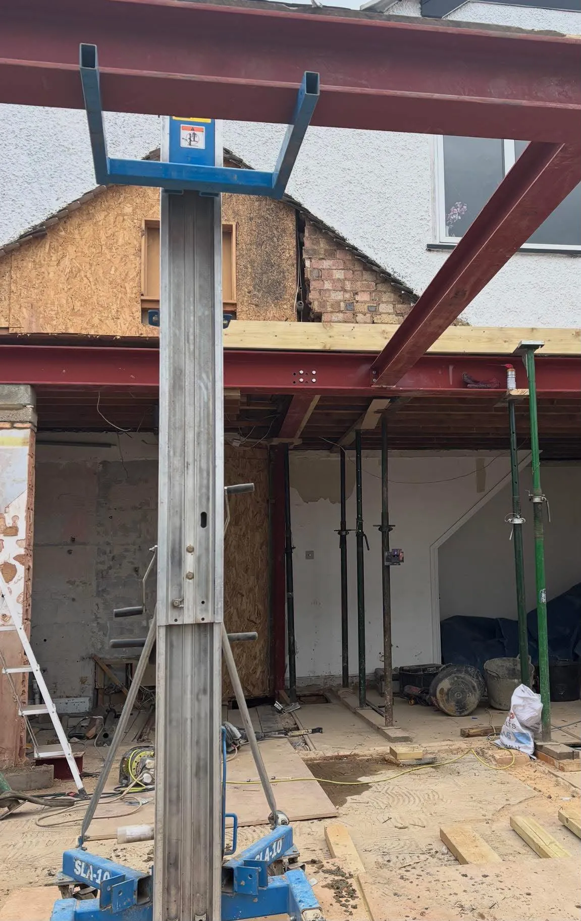 Red steel beams lifted into place at the back of a house