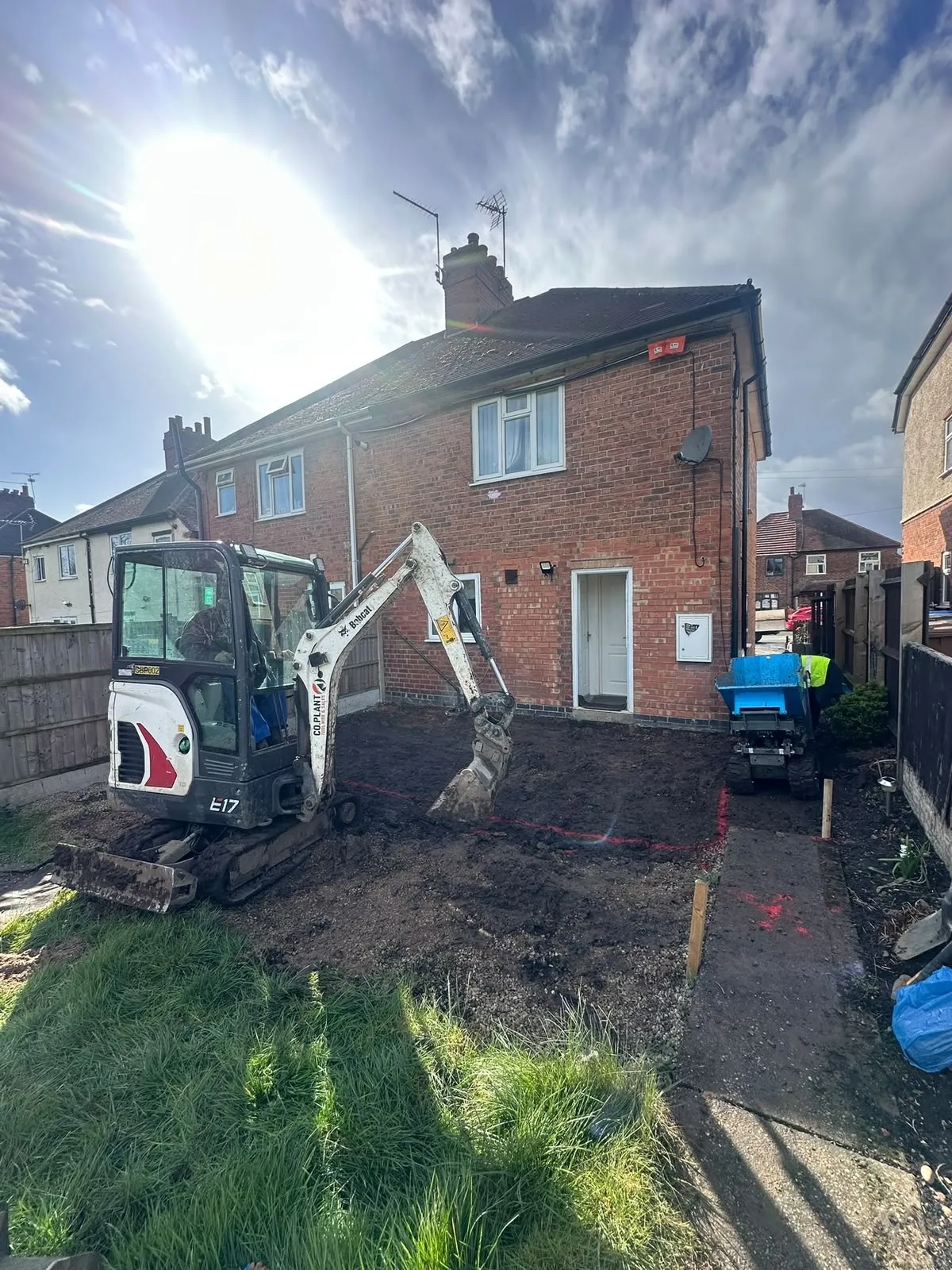 Mini digger starting to dig the back garden of a house