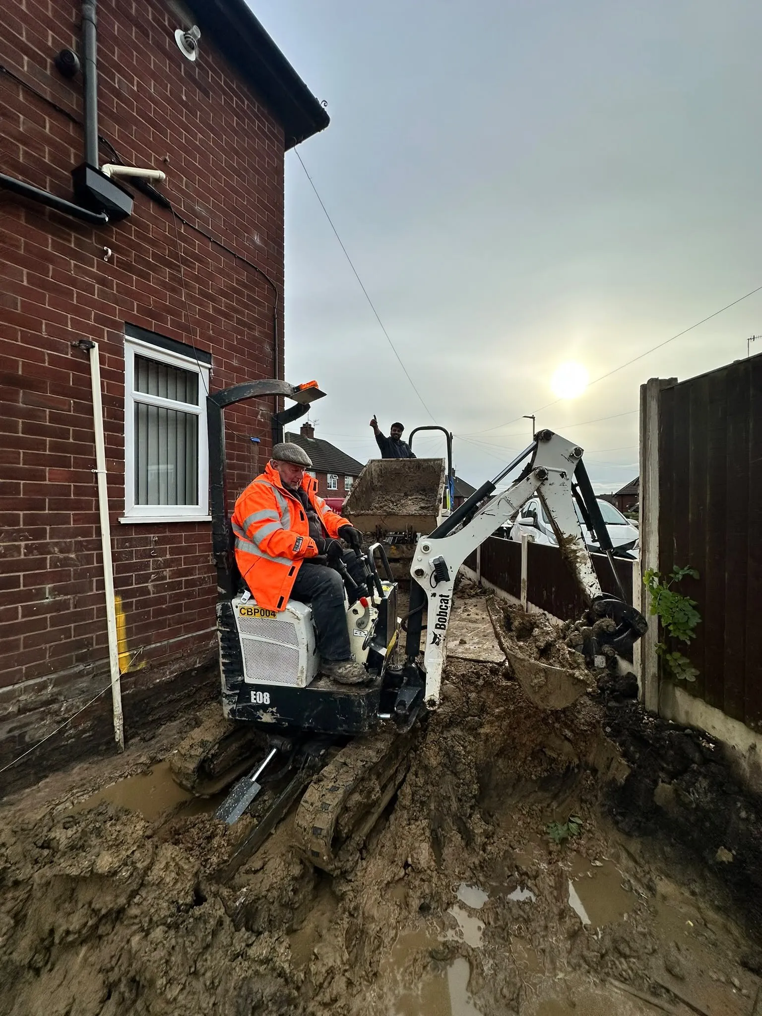 Mini digger working beside a house