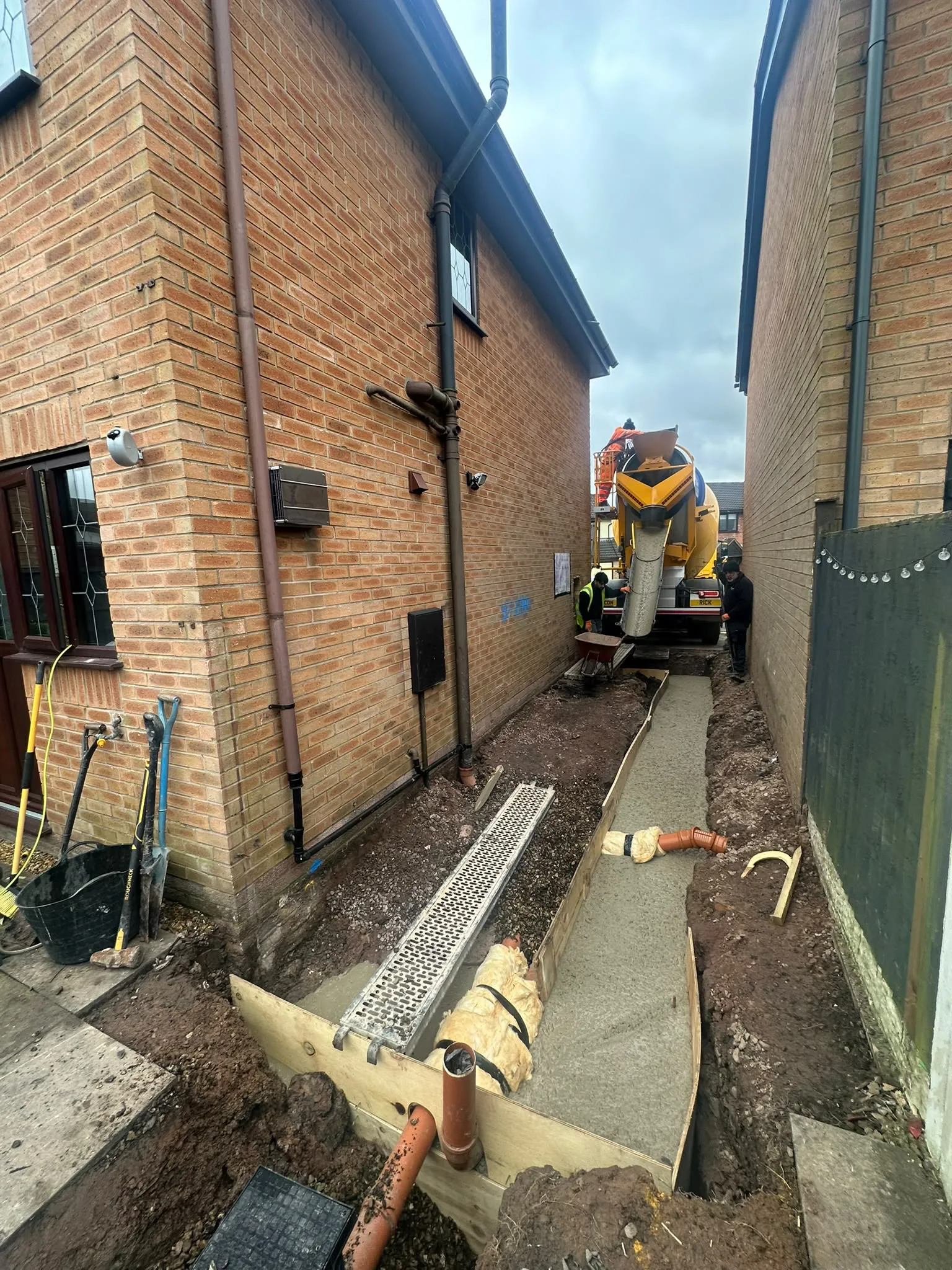 Concrete mixer lorry at the end of a side passage being dug for foundations
