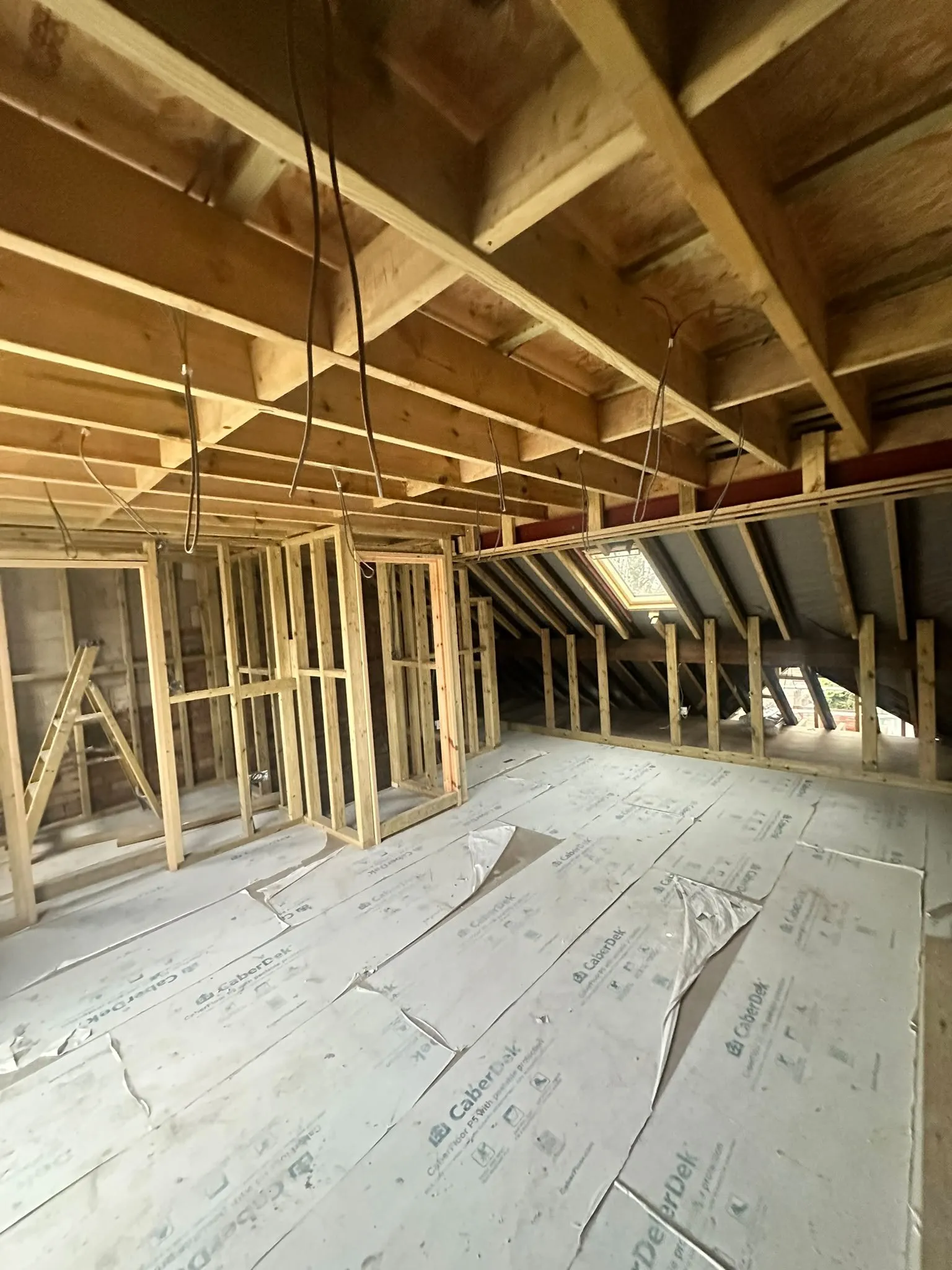 Loft being converted, with new timber stud walls, floor boards and a roof window