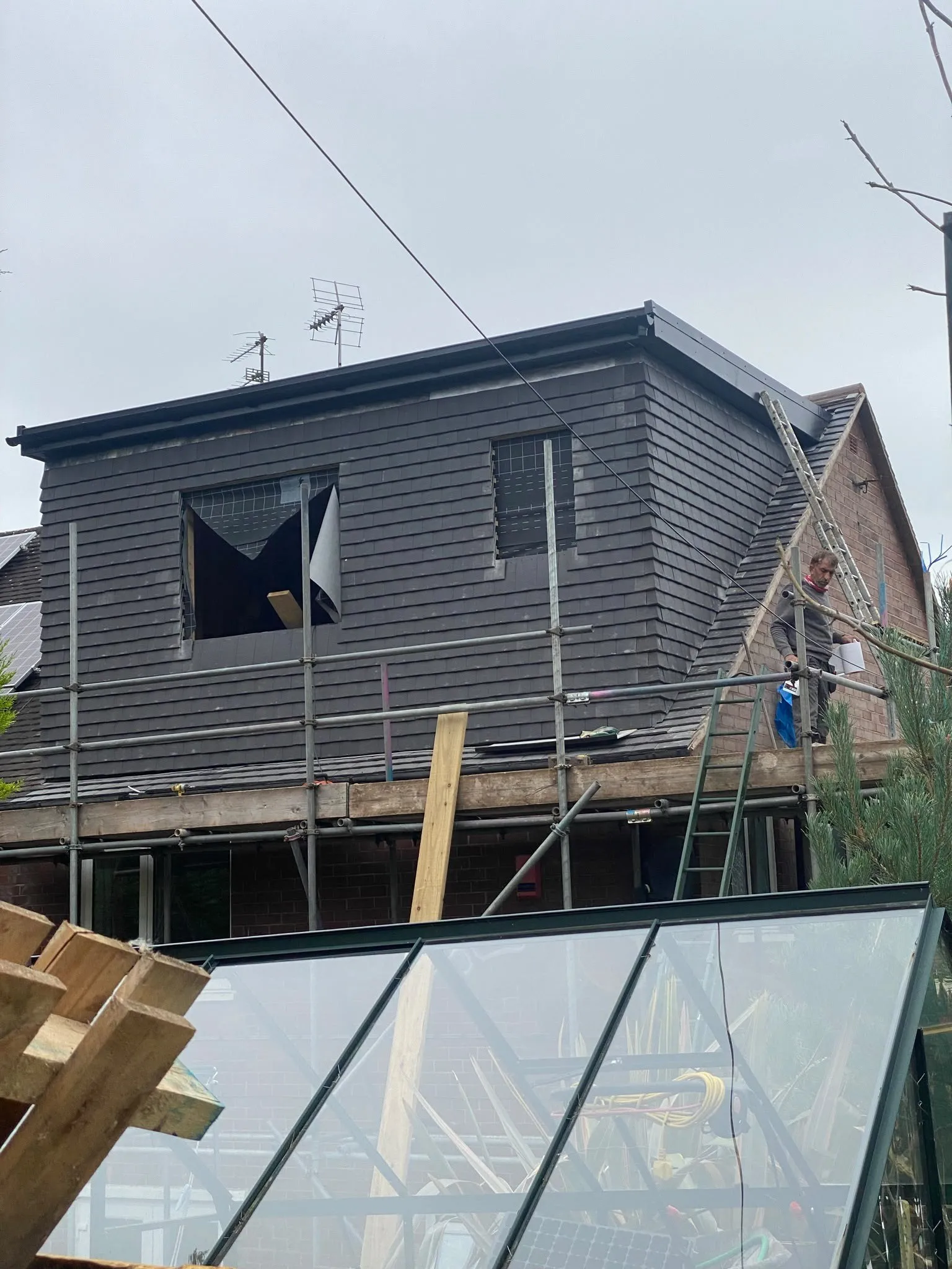 Dormer being clad in dark boards, with scaffolding along the house