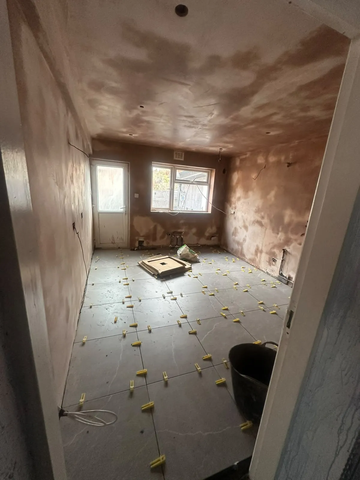 Freshly plastered room with floor tiles being laid
