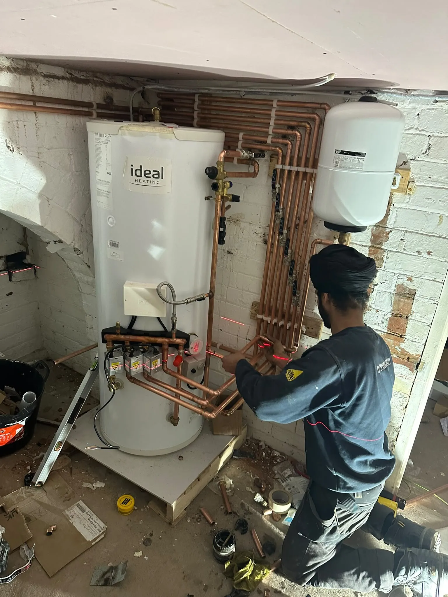 Engineer connecting copper pipework to a new hot water cylinder