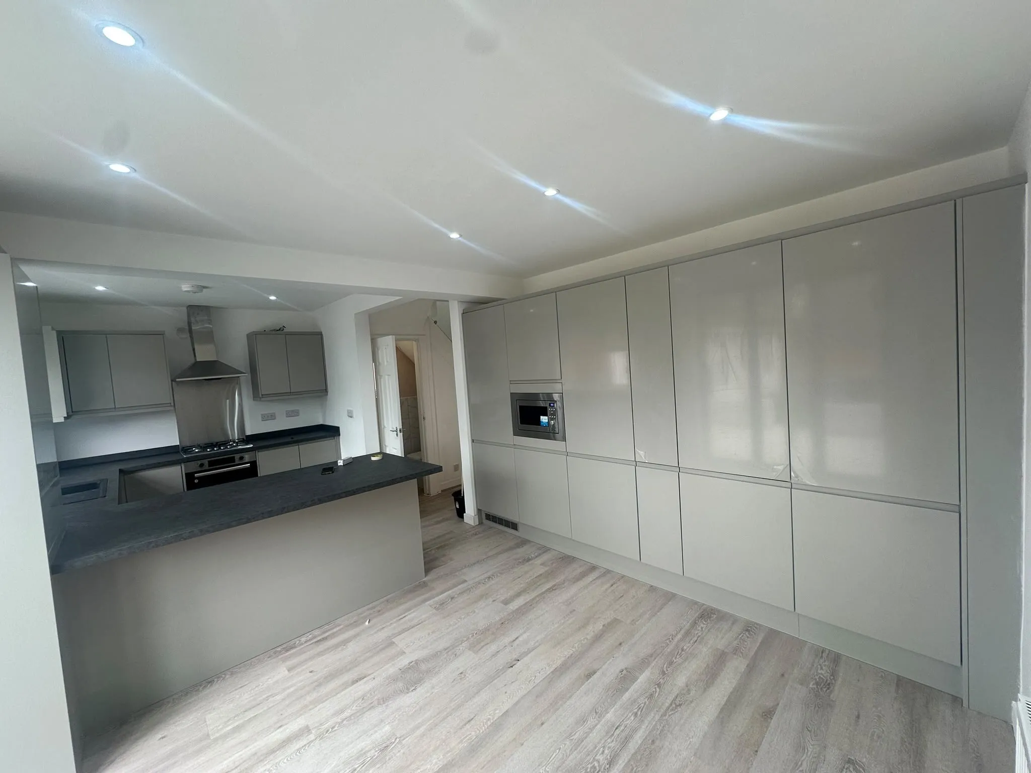 Open-plan kitchen with tall grey units, an island and wood-effect flooring