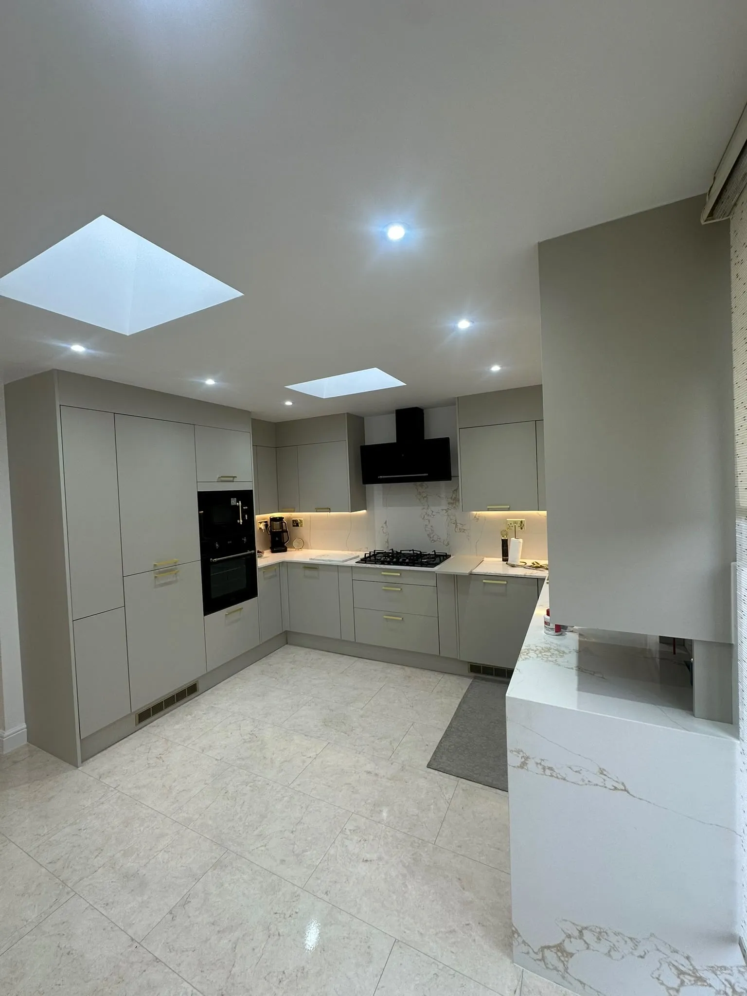Bright kitchen with grey units, white worktops and two roof windows