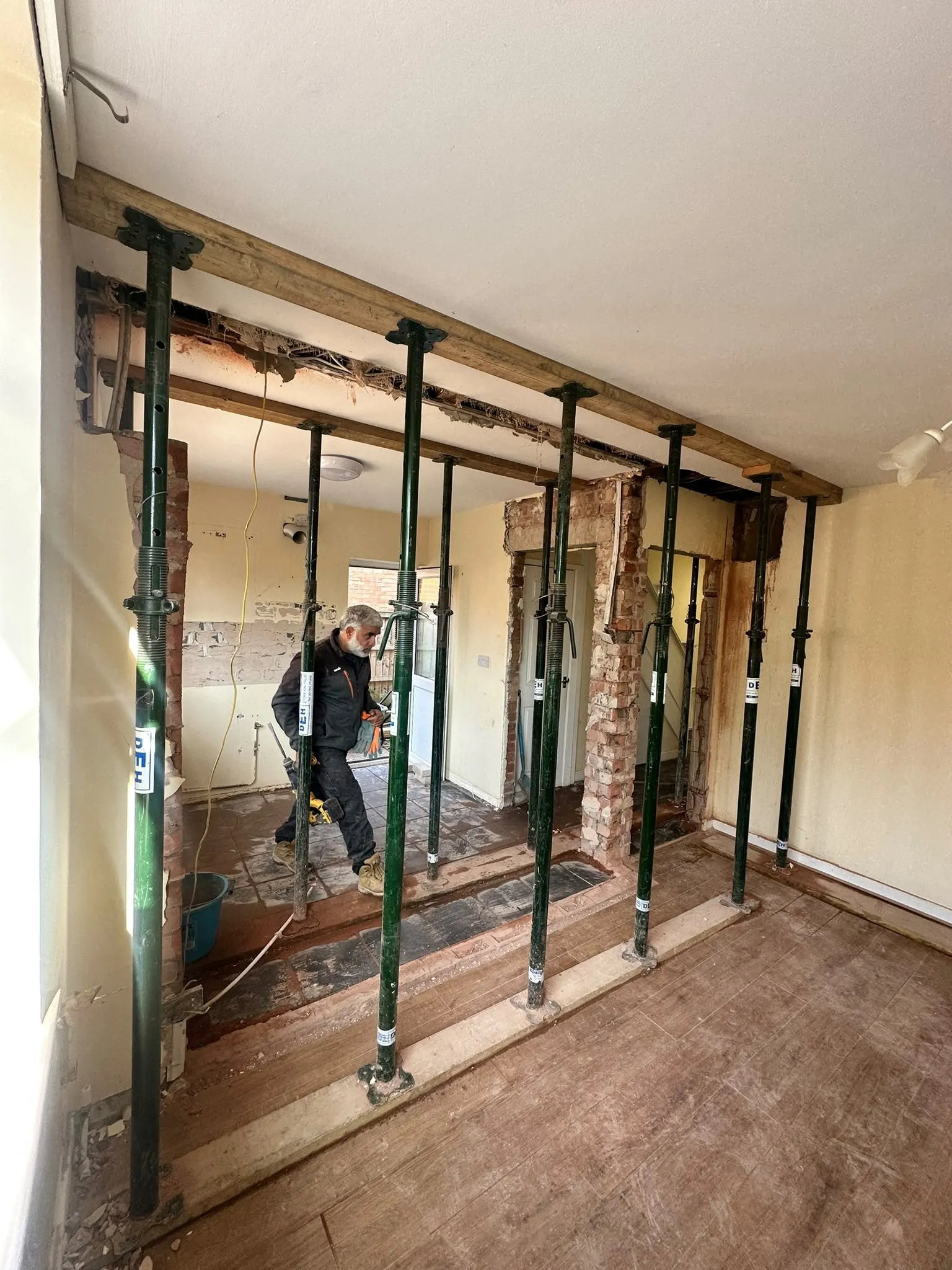 Wall opened up between two rooms with metal props holding the ceiling