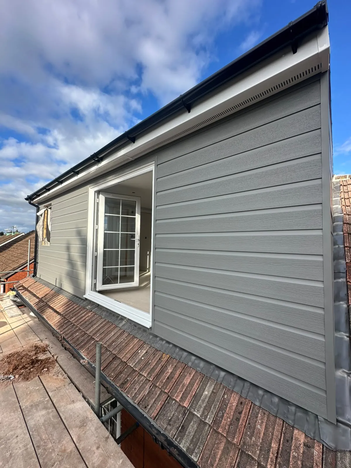 Finished dormer with grey cladding, white fascia and glazed doors