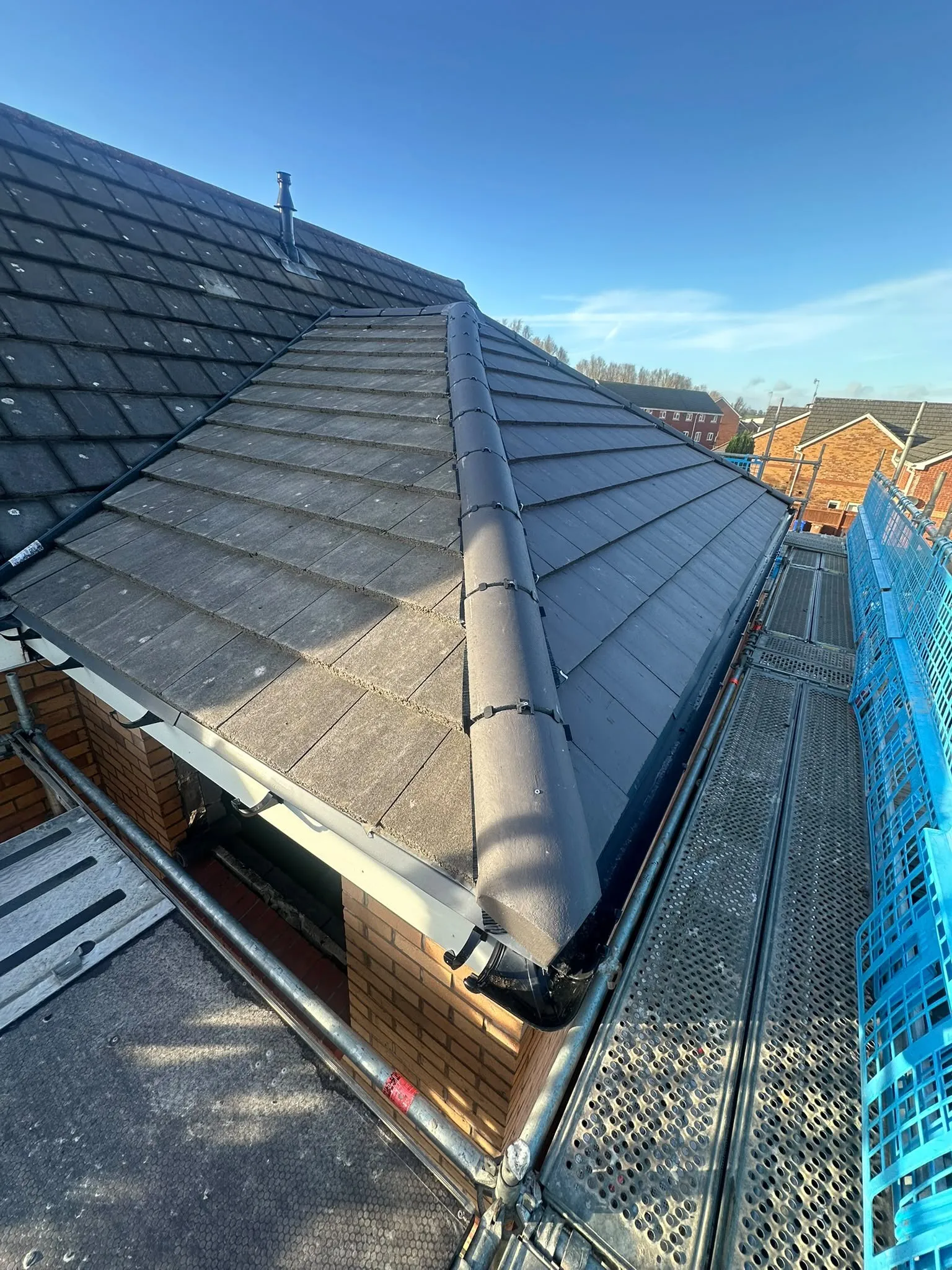 New tiled roof with a neat ridge and hip, seen from scaffolding